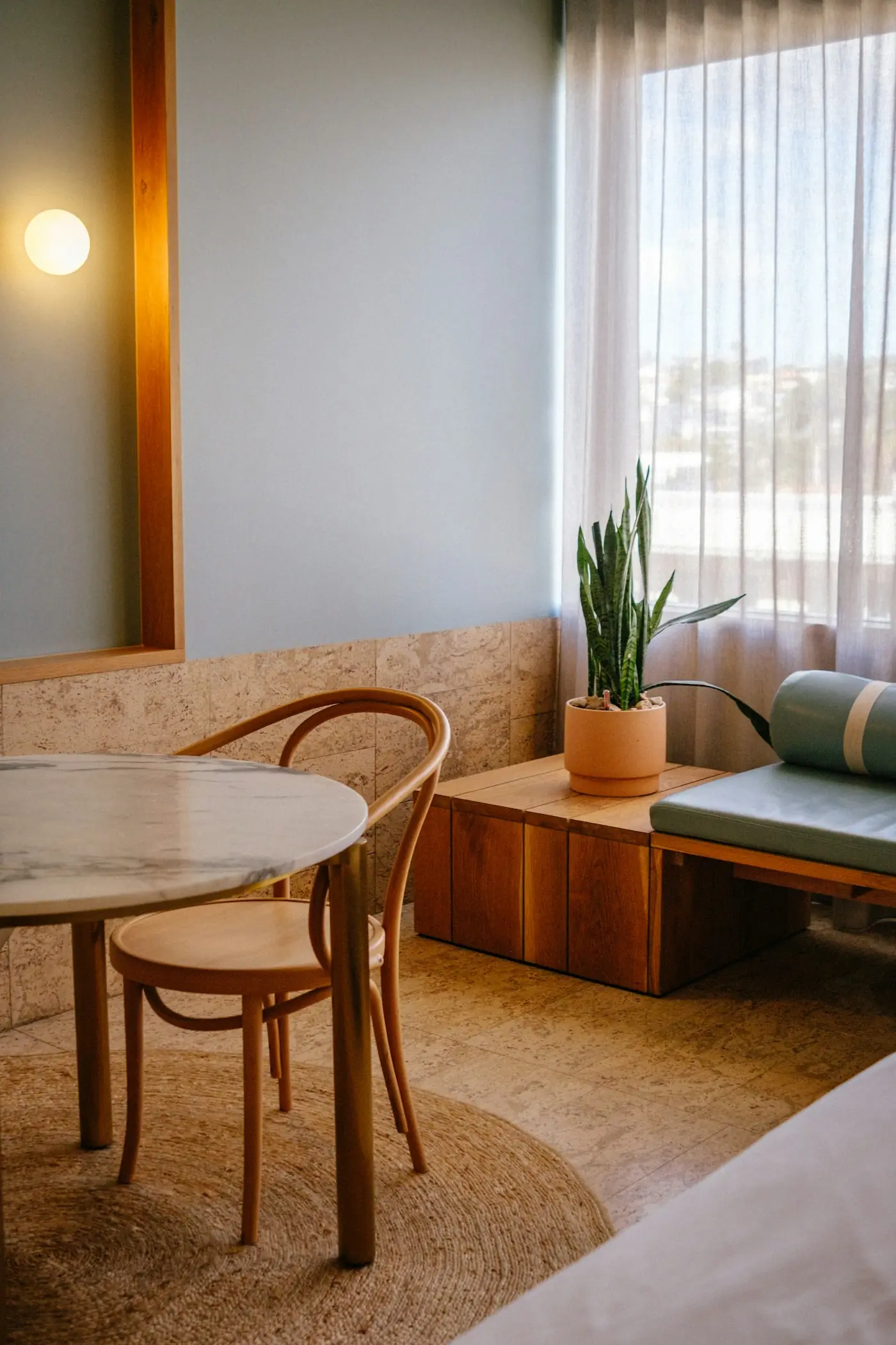 A sunlit room with a marble table and a plant